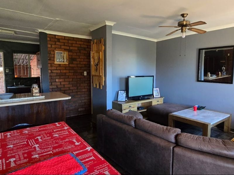 Open plan living and dining area featuring an exposed brick accent wall, breakfast bar, and ceiling fan, creating a functional and connected living space.