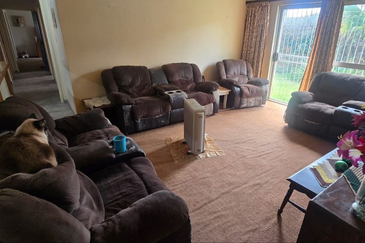 A spacious living room featuring carpet flooring and a sliding glass door providing access to the garden area.