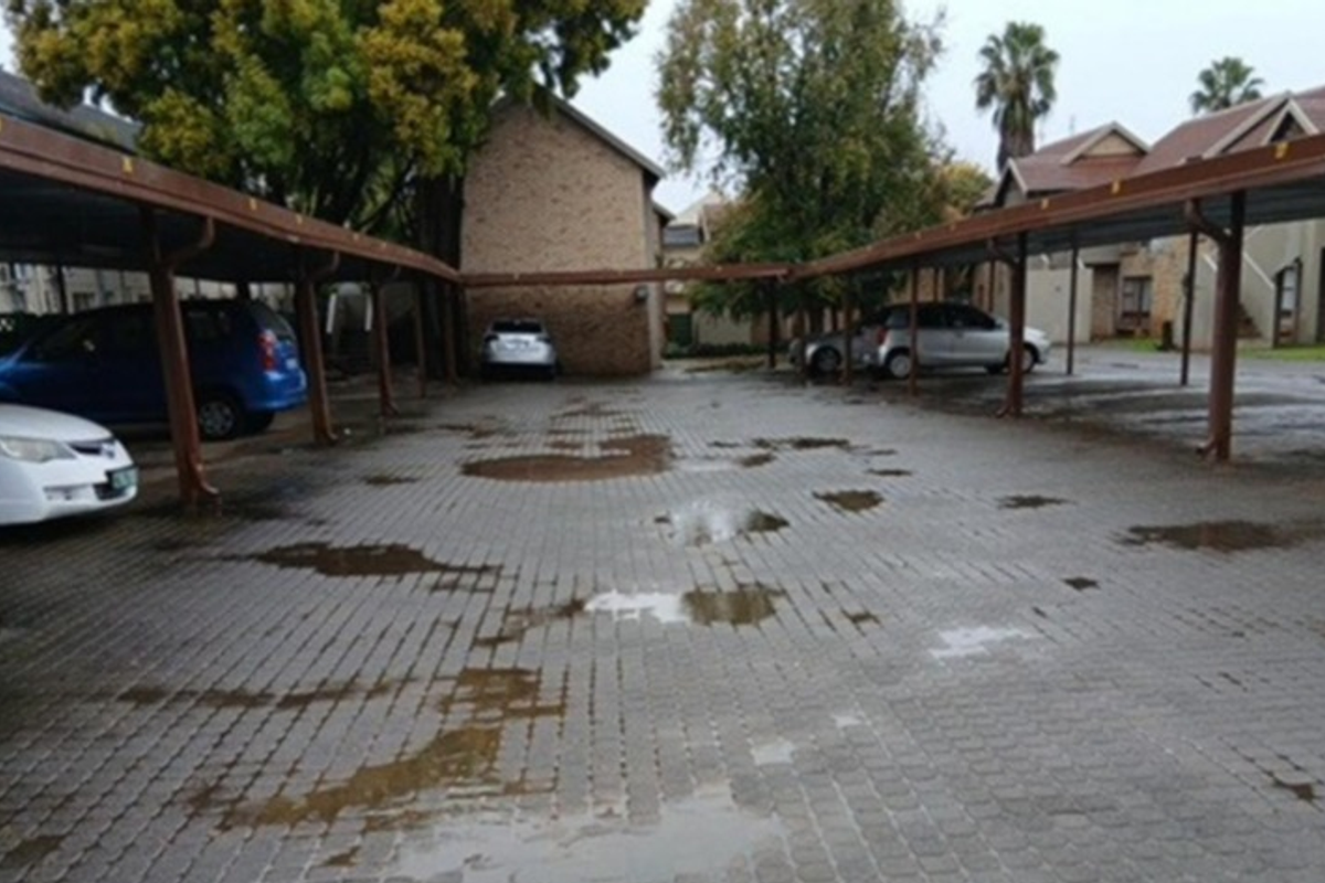 Covered parking area with paved driveway and steel support structures for the townhouse complex.