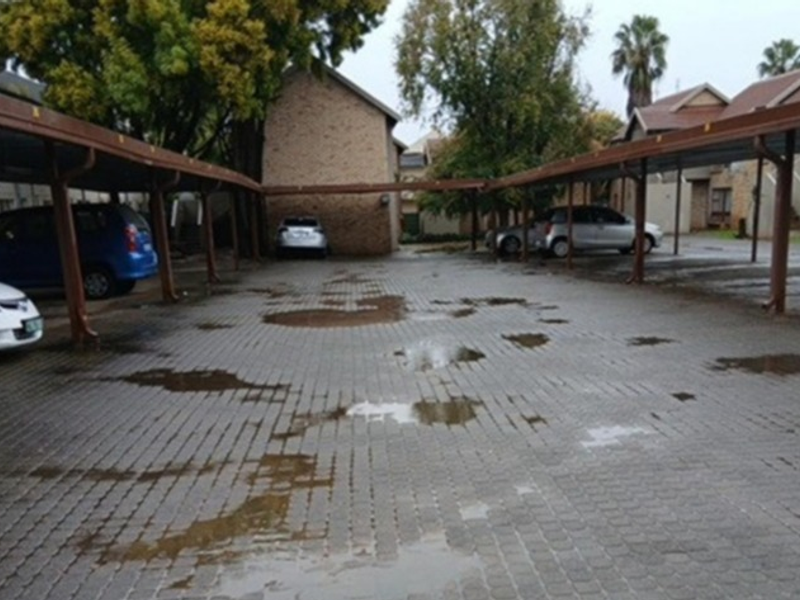 Covered parking area with paved driveway and steel support structures for the townhouse complex.