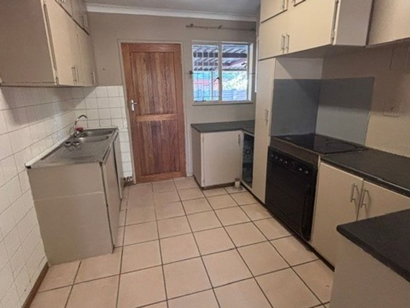 A functional kitchen featuring built-in cabinetry, laminate countertops, a stainless steel sink, and a built-in oven with a ceramic cooktop.
