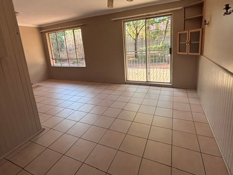 Spacious living area featuring ceramic tile flooring, built-in wall cabinetry, wainscoting, and sliding glass doors providing access to the outdoor area.