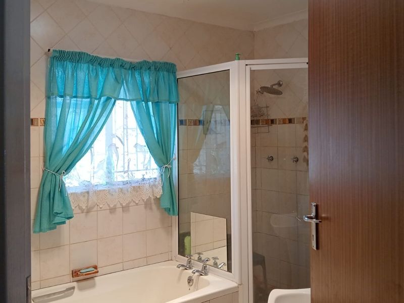 A functional bathroom featuring a bathtub, a separate shower enclosure, and tiled wall finishes.