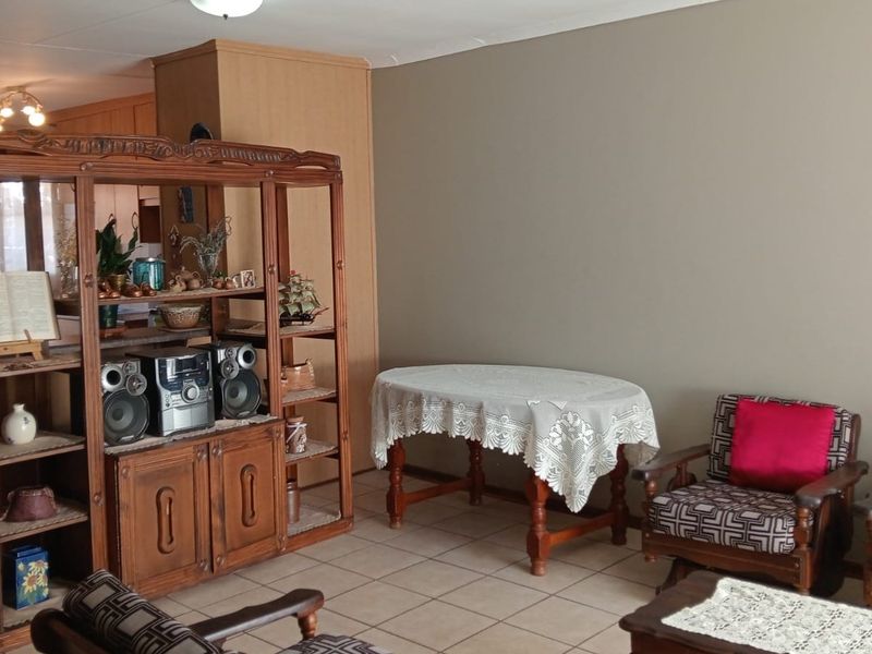 Open plan living and dining area featuring tiled flooring and adjacent kitchen cabinetry, offering a functional layout for daily living.
