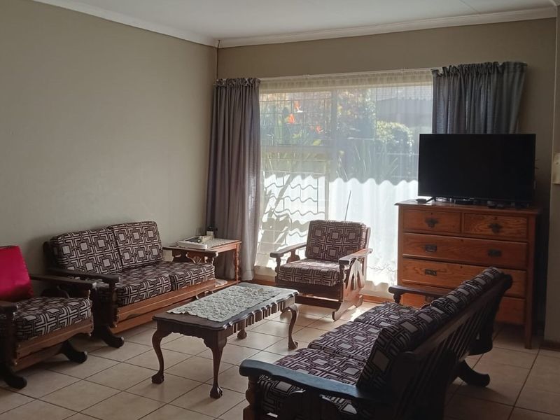 A comfortable living room featuring tiled flooring and a large window that allows for natural light.