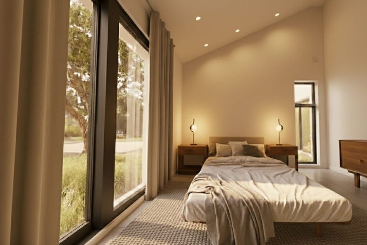 A bright, modern bedroom featuring a raked ceiling, recessed lighting, and large sliding glass doors that provide ample natural light and garden views.