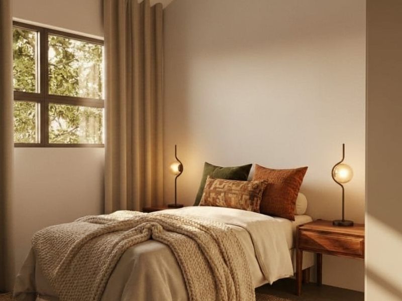 A cozy, well-lit bedroom featuring a window with neutral curtains, creating a warm and inviting atmosphere.