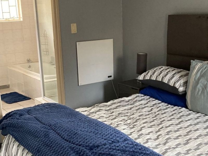A bedroom featuring an en-suite bathroom with a built-in bathtub, tiled flooring, and a wall-mounted heater.