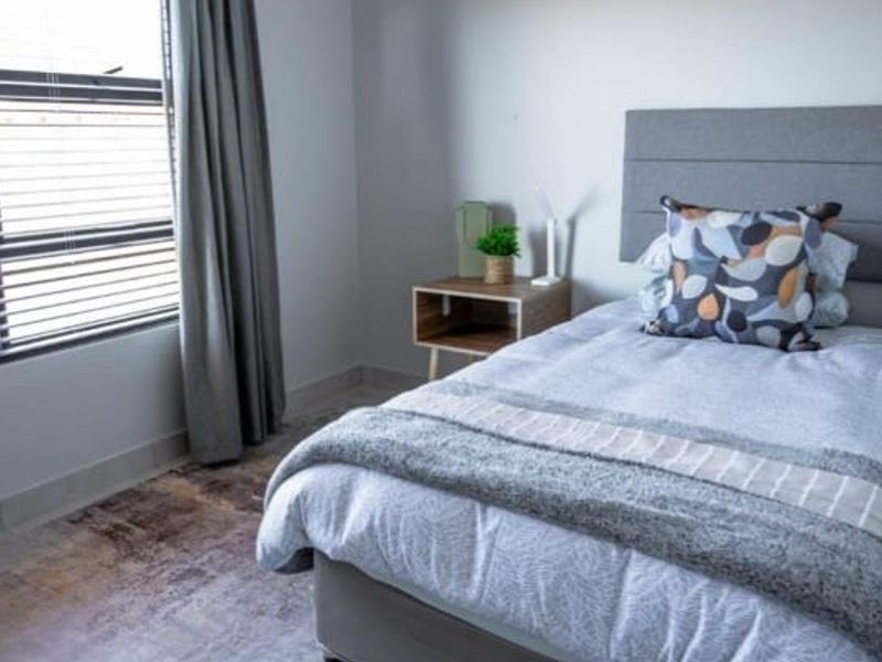 A well-maintained bedroom featuring neutral walls, modern skirting boards, and large windows fitted with venetian blinds for adjustable natural light.