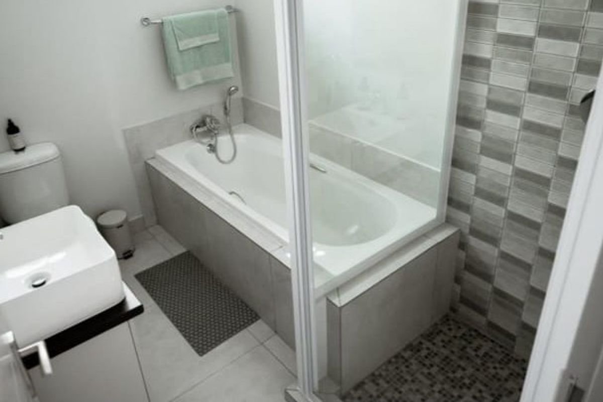 Modern bathroom featuring a bathtub, separate shower enclosure, basin, and toilet with neutral tiled finishes.