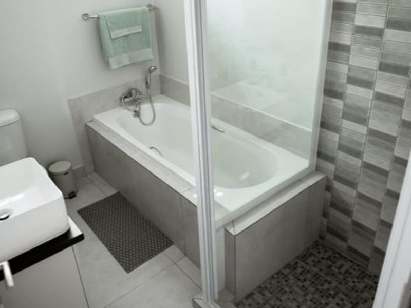 Modern bathroom featuring a bathtub, separate shower enclosure, basin, and toilet with neutral tiled finishes.