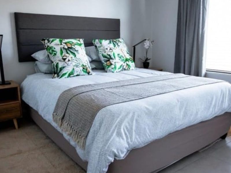 A well-maintained bedroom featuring neutral wall finishes, tiled flooring, and a large window with fitted blinds for natural light.