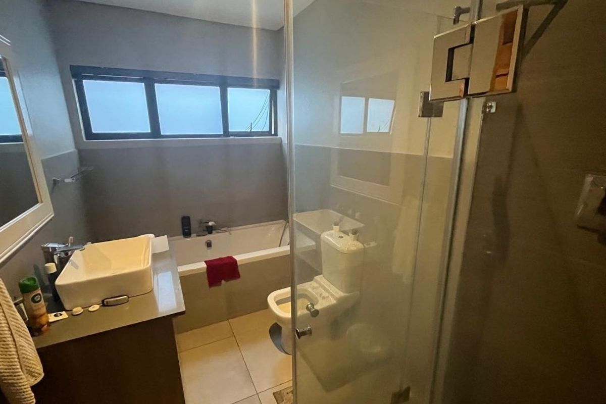 A functional bathroom featuring a built-in vanity with a vessel sink, a bathtub, a toilet, and a separate glass-enclosed shower area.