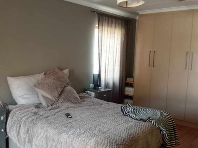 A functional bedroom featuring laminate flooring and ample built-in cupboard storage space.