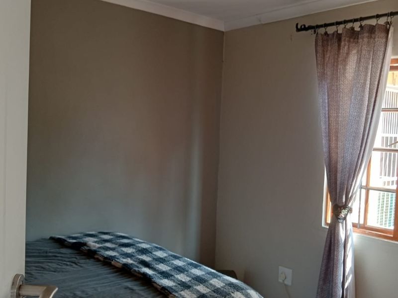 A bedroom featuring neutral painted walls, coving, and a timber-framed window with curtain fixtures.