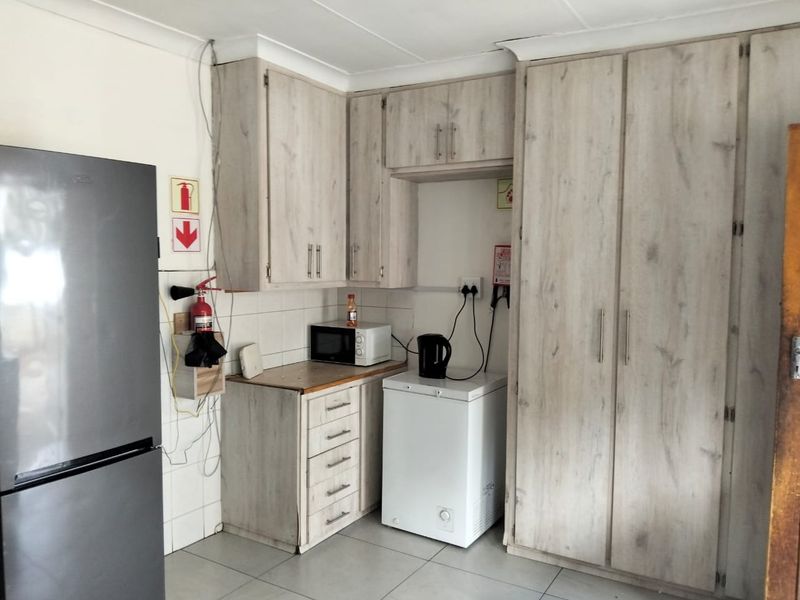 A functional kitchen area featuring light wood-look cabinetry, tiled backsplash, and ample storage space with a built-in pantry cupboard.