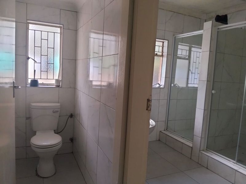 A functional bathroom featuring a separate toilet area and a shower enclosure with tiled finishes throughout.