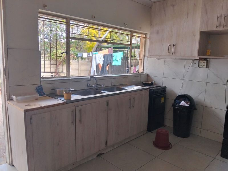 Functional kitchen featuring tiled splashbacks, double sink, and built-in cabinetry with a freestanding stove.