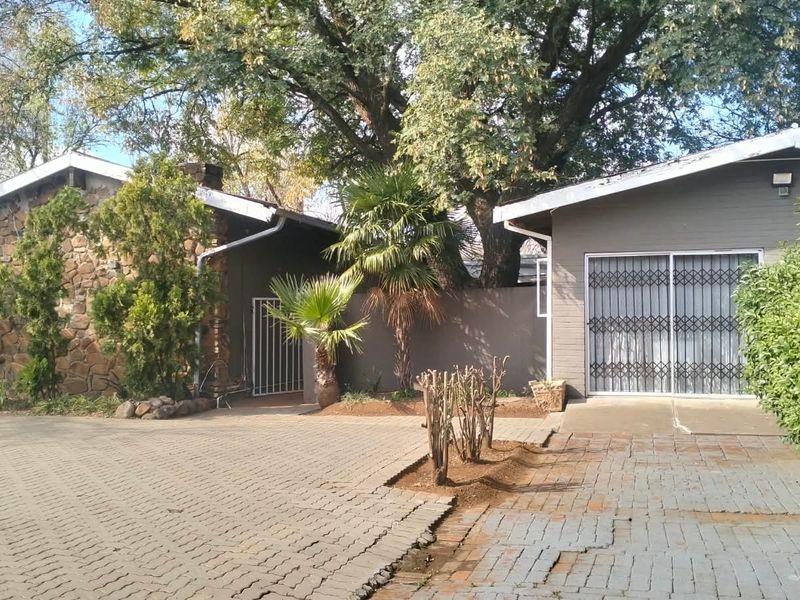 Front exterior view of the property featuring a paved driveway, stone cladding, and a secure garage entrance.