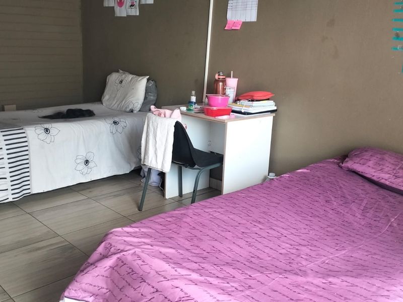 A functional bedroom featuring tiled flooring and neutral wall finishes, suitable for multi-occupancy or guest accommodation.