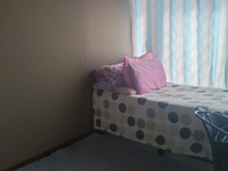 A simple bedroom featuring a window with curtains, providing natural light to the space.
