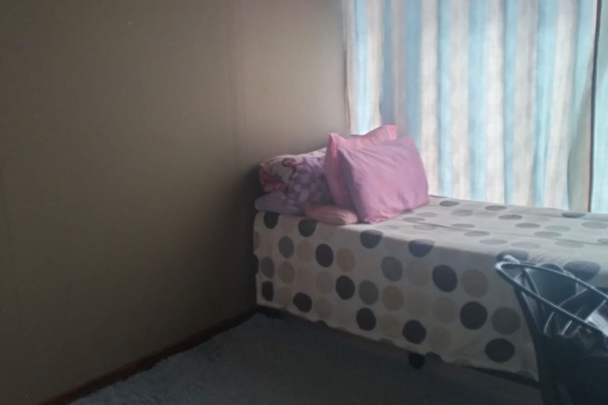 A simple bedroom featuring a window with curtains, providing natural light to the space.
