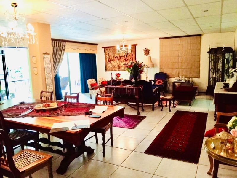 Spacious open-plan living and dining area featuring tiled flooring, drop ceilings, and large sliding glass doors leading to an outdoor space.
