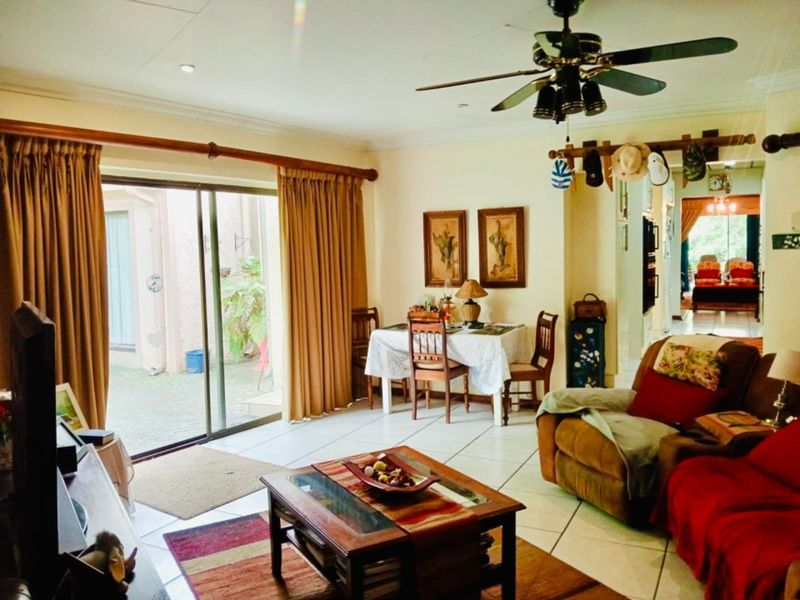 Spacious living room featuring tiled flooring, a ceiling fan, and large sliding glass doors providing direct access to the outdoor patio area.