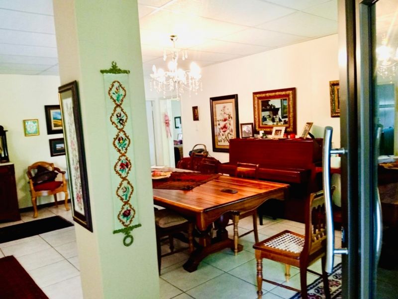 A dining area featuring tiled flooring, a drop ceiling, and a central chandelier, providing a functional space for meals.