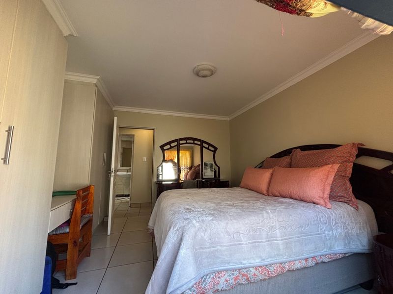 A bedroom featuring built-in cupboards, tiled flooring, and decorative cornicing, with direct access to an en-suite bathroom.
