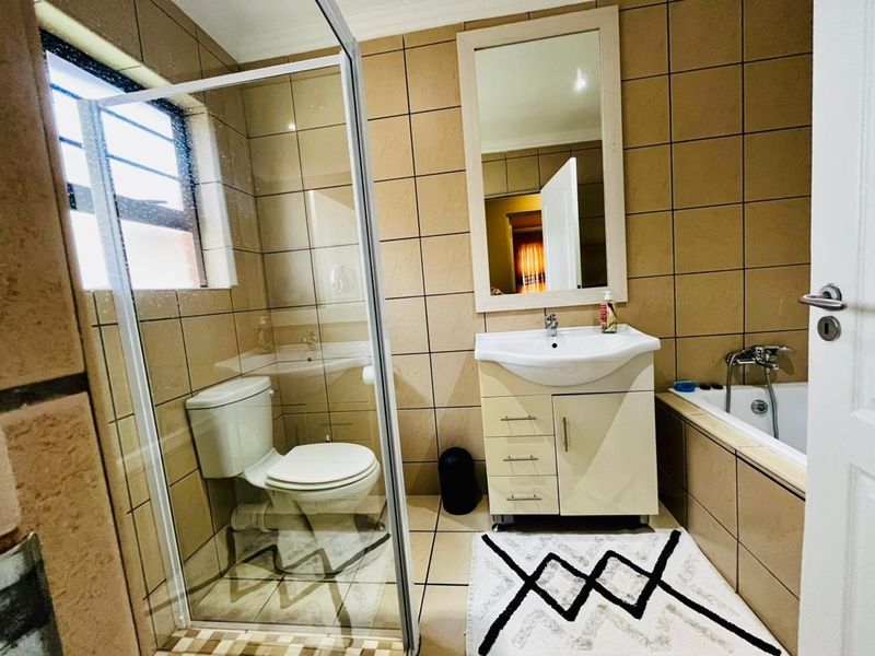 A functional bathroom featuring a shower enclosure, vanity basin, and a built-in bathtub with tiled wall finishes.