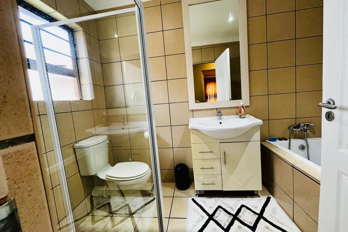 A functional bathroom featuring a shower enclosure, vanity basin, and a built-in bathtub with tiled wall finishes.