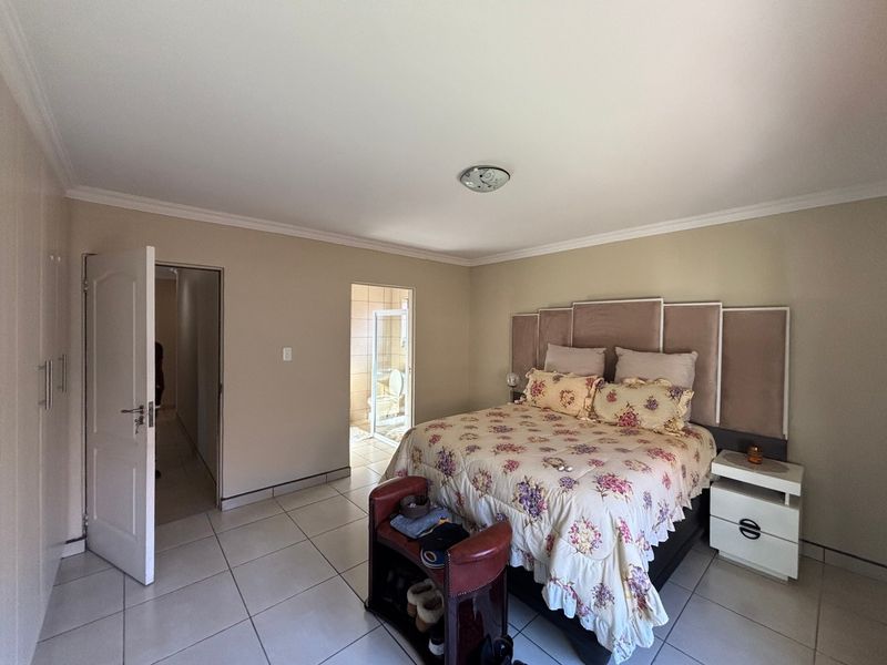Spacious bedroom featuring tiled flooring, built-in cupboards, and direct access to an en-suite bathroom.