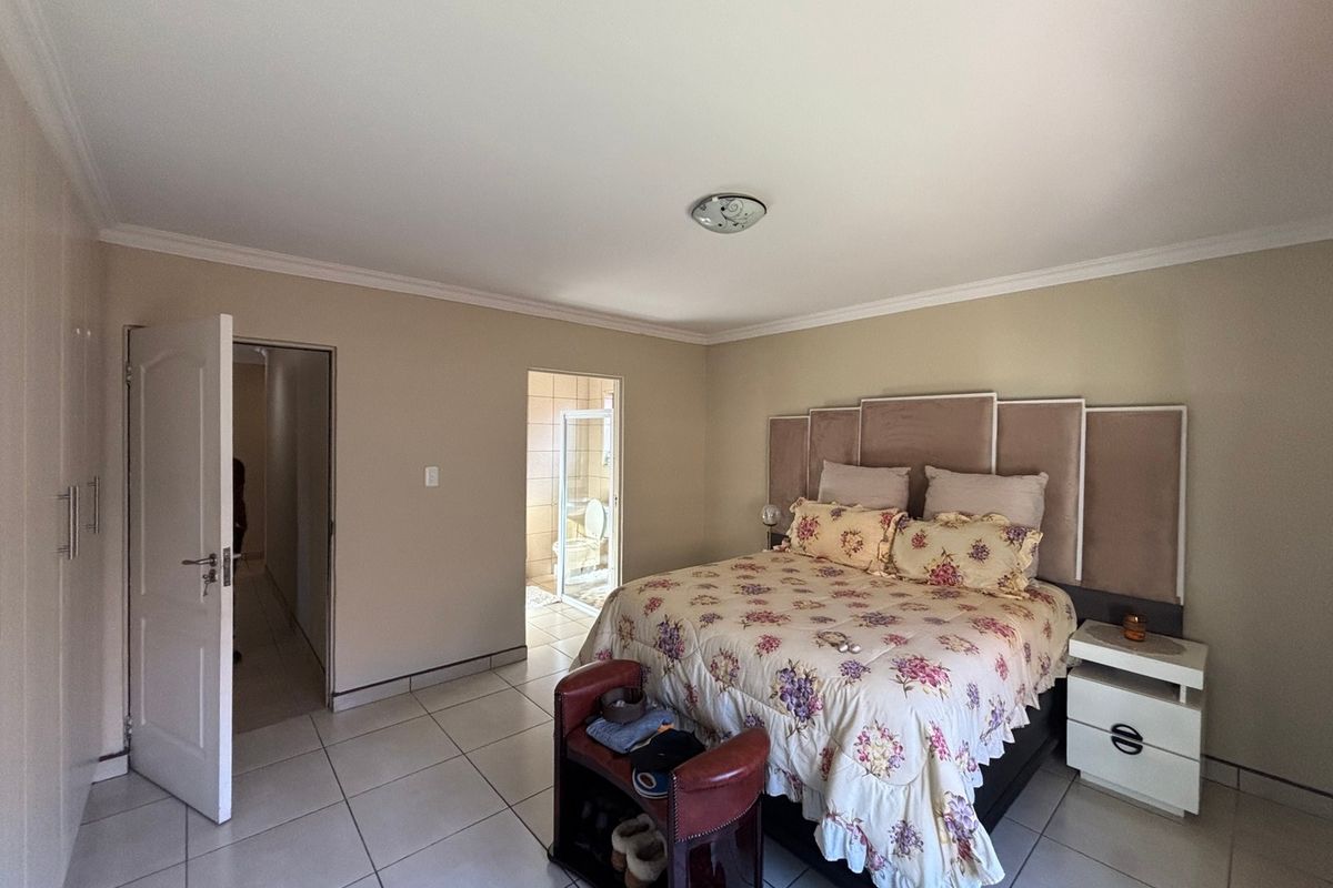 Spacious bedroom featuring tiled flooring, built-in cupboards, and direct access to an en-suite bathroom.