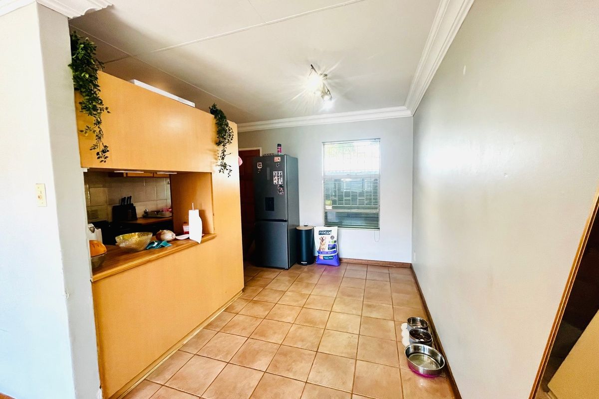 A functional kitchen area featuring tiled flooring, built-in cabinetry, and a window with blinds, offering a practical layout for daily use.