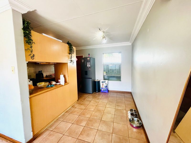A functional kitchen area featuring tiled flooring, built-in cabinetry, and a window with blinds, offering a practical layout for daily use.