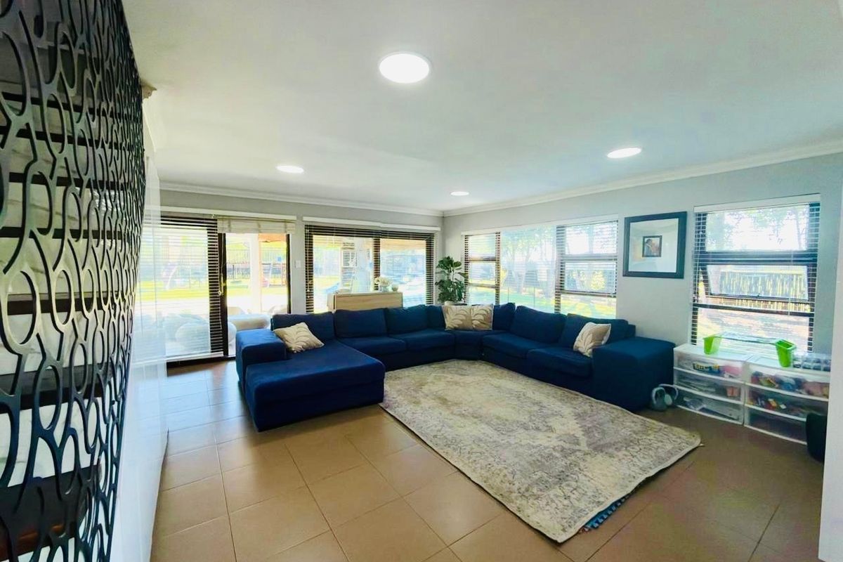 Spacious living room featuring large windows, sliding glass doors providing natural light, and modern tiled flooring throughout.