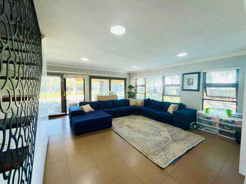 Spacious living room featuring large windows, sliding glass doors providing natural light, and modern tiled flooring throughout.