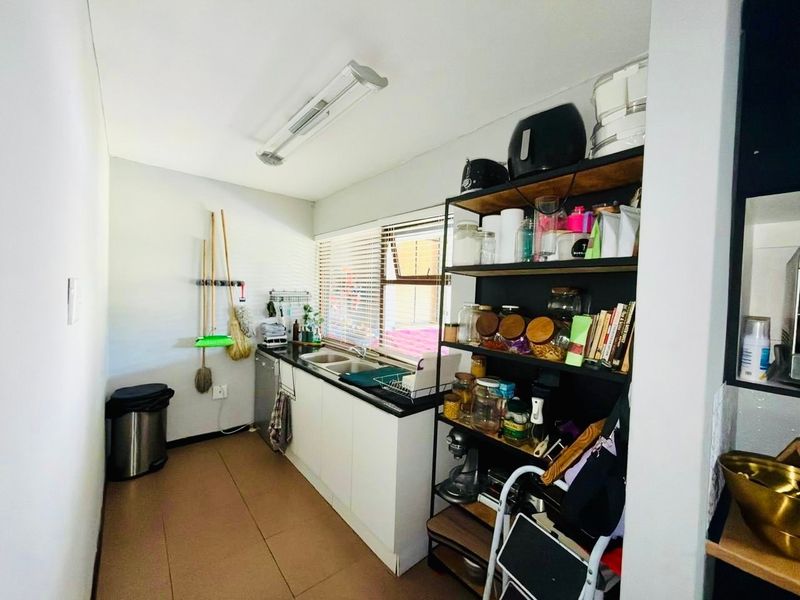 Functional scullery area featuring a double basin sink, built-in cabinetry, and tiled flooring, providing practical utility space for the home.