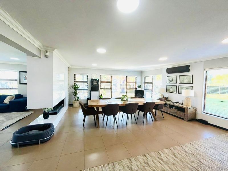 Spacious open-plan living and dining area featuring tiled floors, a modern built-in fireplace, recessed lighting, and an integrated air conditioning unit.