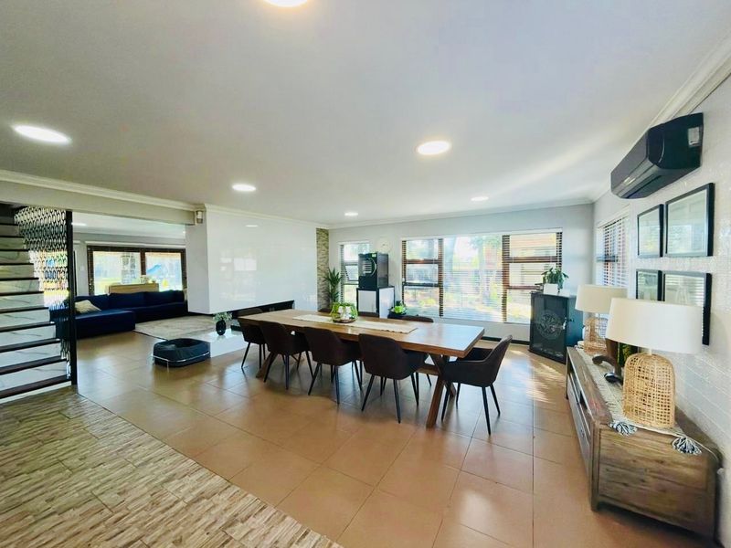 Spacious open-plan living and dining area featuring tiled floors, recessed lighting, a built-in fireplace, and an air conditioning unit.