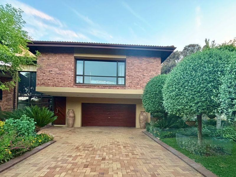 A well-maintained double-story home featuring a classic brick facade, a paved driveway, and a neatly landscaped front garden.