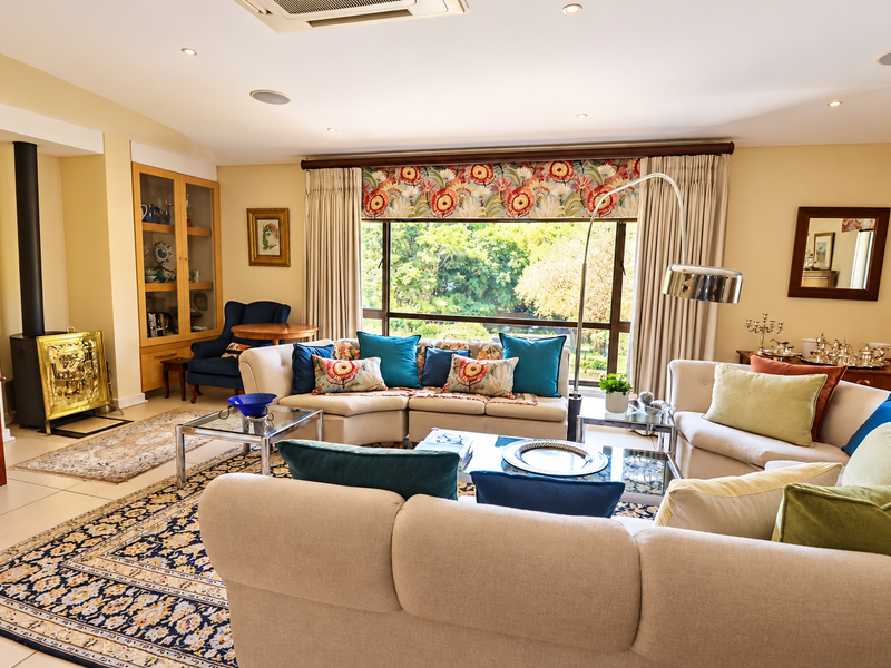 Spacious living room featuring a freestanding fireplace, built-in display cabinetry, recessed lighting, and a large window with garden views.