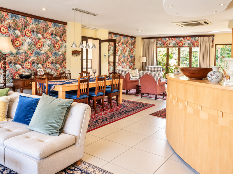 Spacious open-plan living and dining area featuring tiled flooring, recessed lighting, ducted air conditioning, and decorative wallpaper accents.