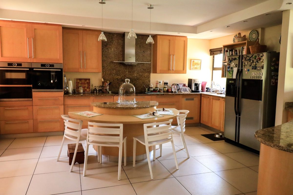 Spacious kitchen featuring light wood cabinetry, granite countertops, integrated oven, and a central breakfast island with tiled flooring throughout.