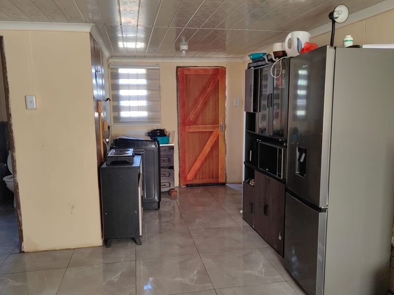 A functional kitchen area featuring tiled flooring, PVC ceiling panels, and a timber door, providing a basic utility space for the home.