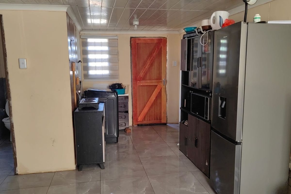 A functional kitchen area featuring tiled flooring, PVC ceiling panels, and a timber door, providing a basic utility space for the home.