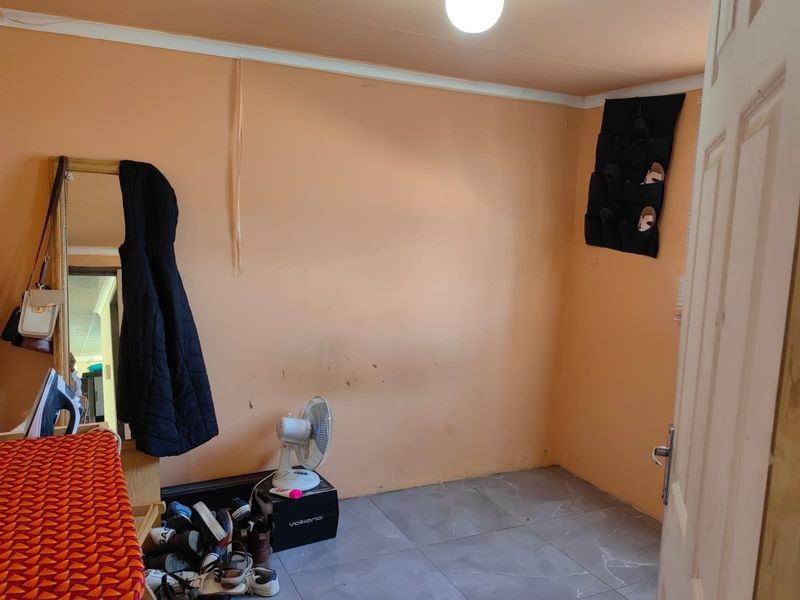 A bedroom featuring tiled flooring and peach-toned walls, currently used as a multi-purpose space.