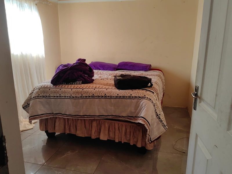 A simple bedroom featuring tiled flooring and neutral wall tones, offering a functional space ready for personalization.