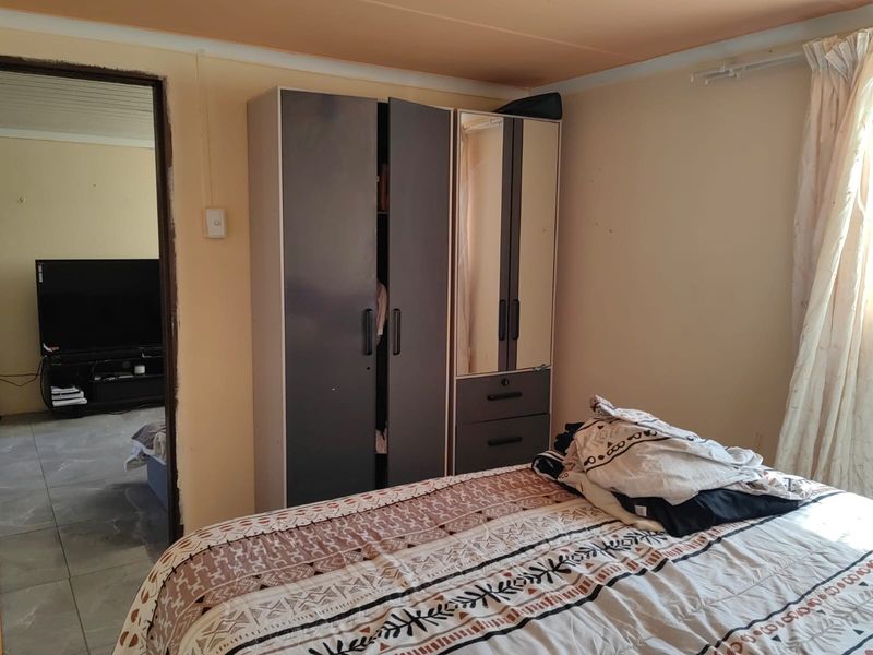 A bedroom featuring a built-in wardrobe, with visible wear on the ceiling and door frame finishes.